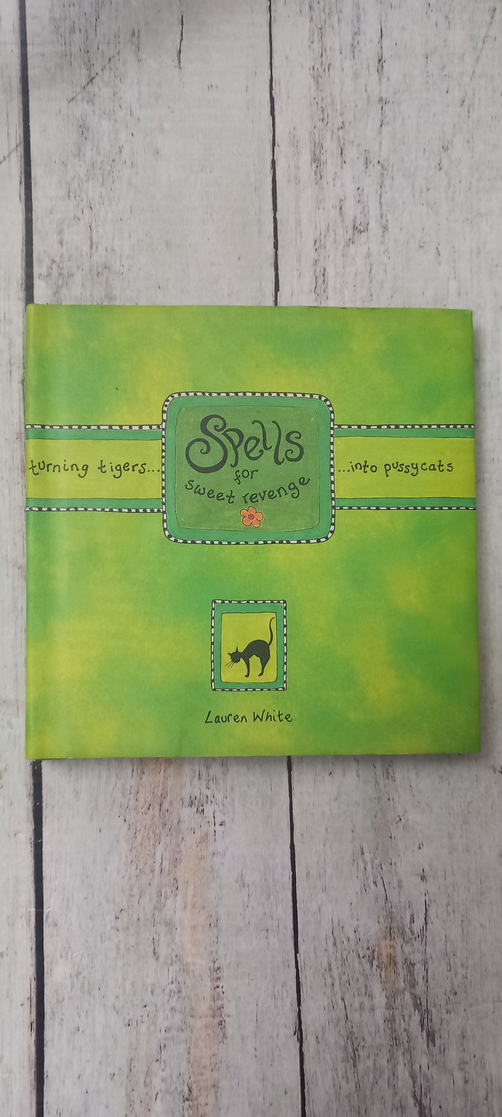 A square green journal or notebook titled 'Scalpers' by Laura Walsh, placed flat on a light gray wood plank surface.