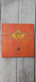 An orange hardcover book titled 'Bells for Bad Boys' by Laura White, featuring a yellow diamond-shaped title label and a small black cat silhouette, displayed on a light gray wood plank surface.
